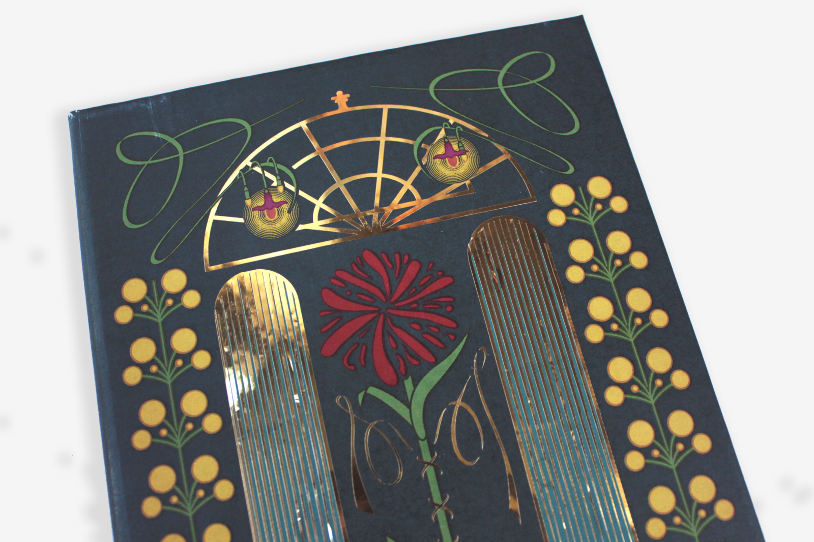 Image of a deep blue notebook with art nouveau inspired designs and gold foil on the cover.